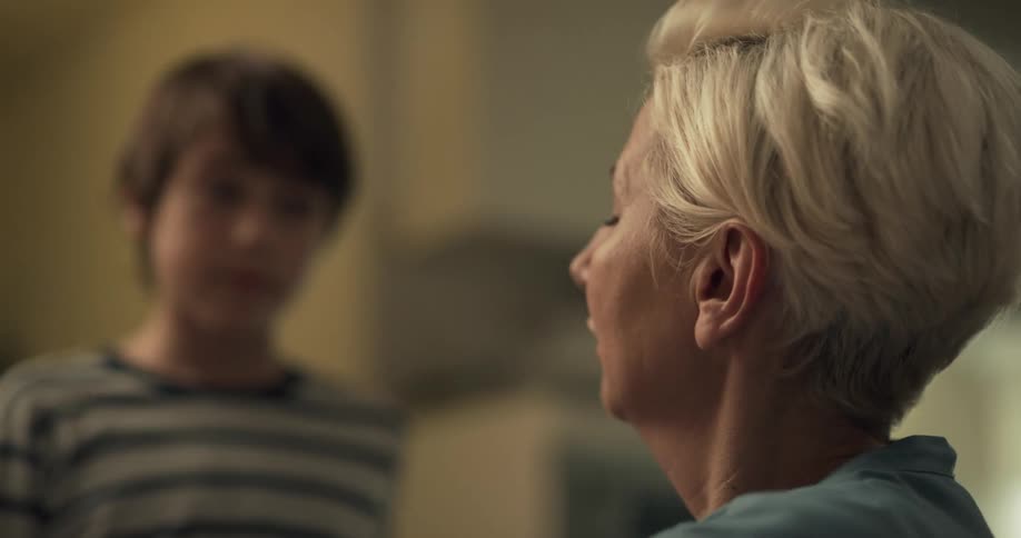 A boy hugs his mom and gets a kiss on a cheek before walking down the hallway