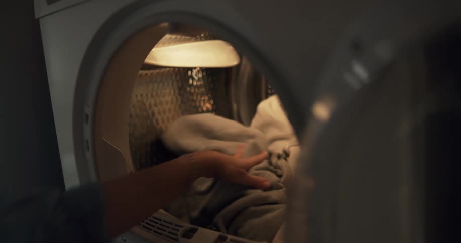 A view of someone loading laundry into a dryer