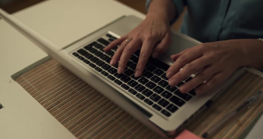 A person typing on a laptop while sitting at a desk