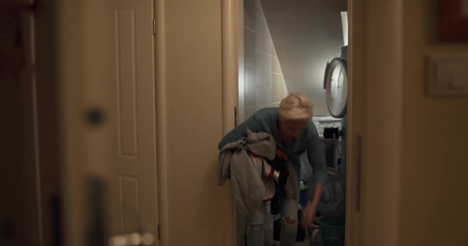 Mother standing setting washing machine catches clothes thrown by son