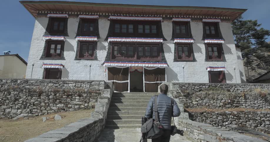 A man in a jacket walks up to a white building