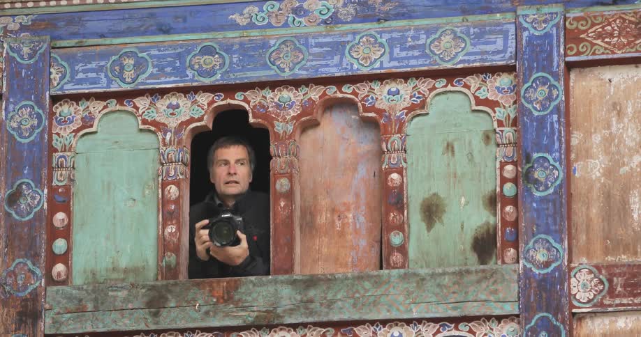 A photographer takes a picture from the window of a brightly colored building