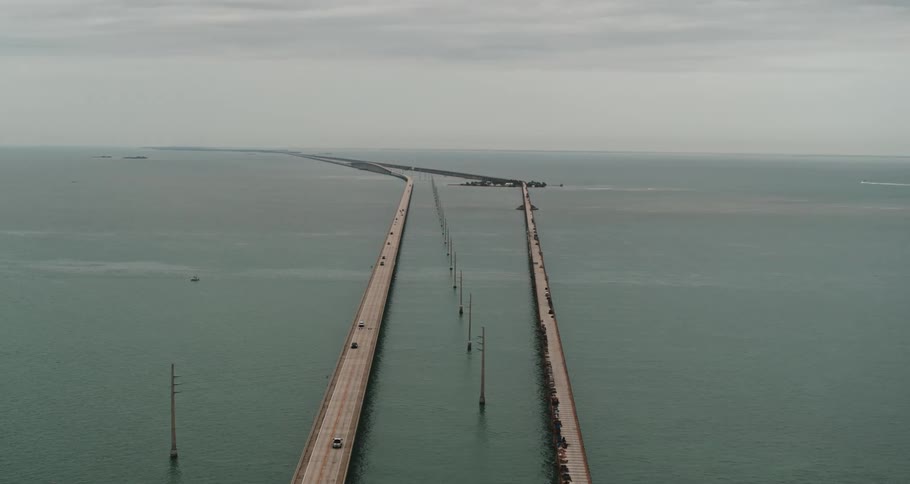 A very long bridge over water is shown that has cars traveling on it