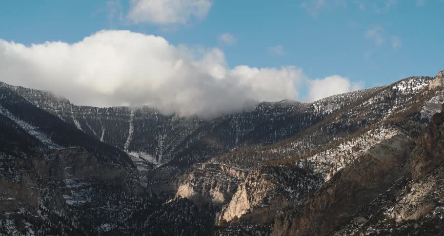 Mountains are shown with a lot of tree coverage and some waterfalls in the distance