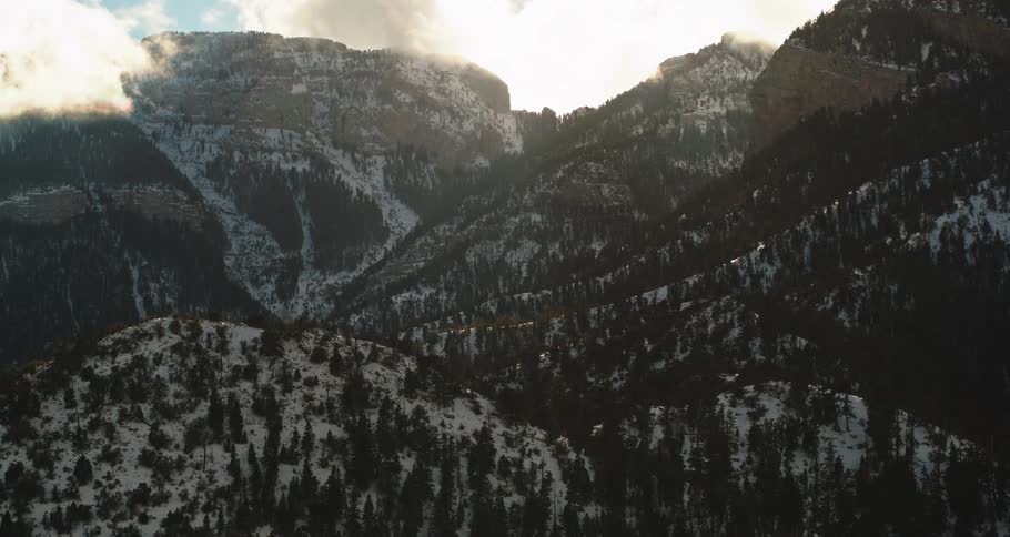 Forested mountains are shown with a sunny sky