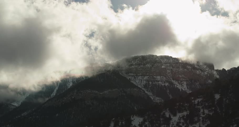 Snow covered mountains filled with pine trees high in the clouds