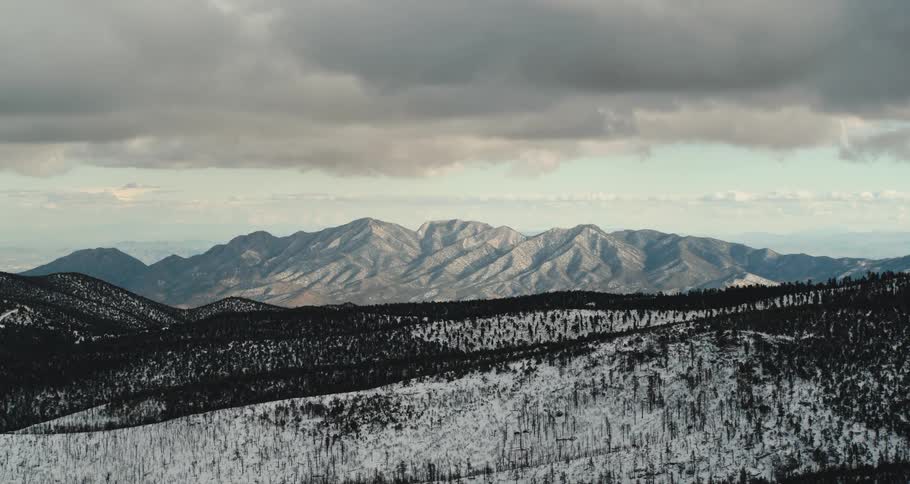 An aerial view of a snowy mountain landscape on a cloudy day