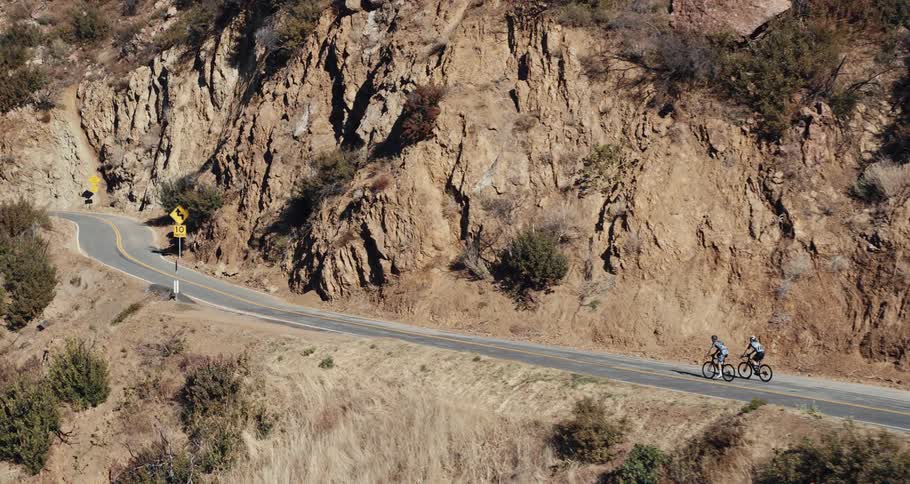 Two cyclists climbing a mountain road at daytime