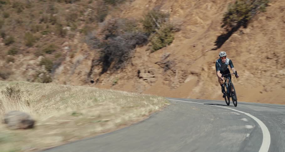 A cyclist meets up with a fellow rider while coming around a bend on a mountain road