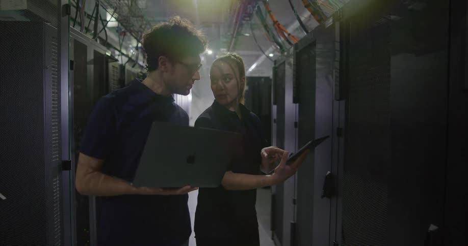 Two coworkers walk through the server room together