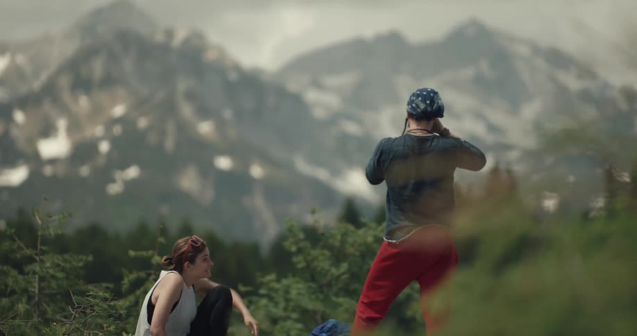 A man and woman are relaxing in the mountains and stand up to take photos