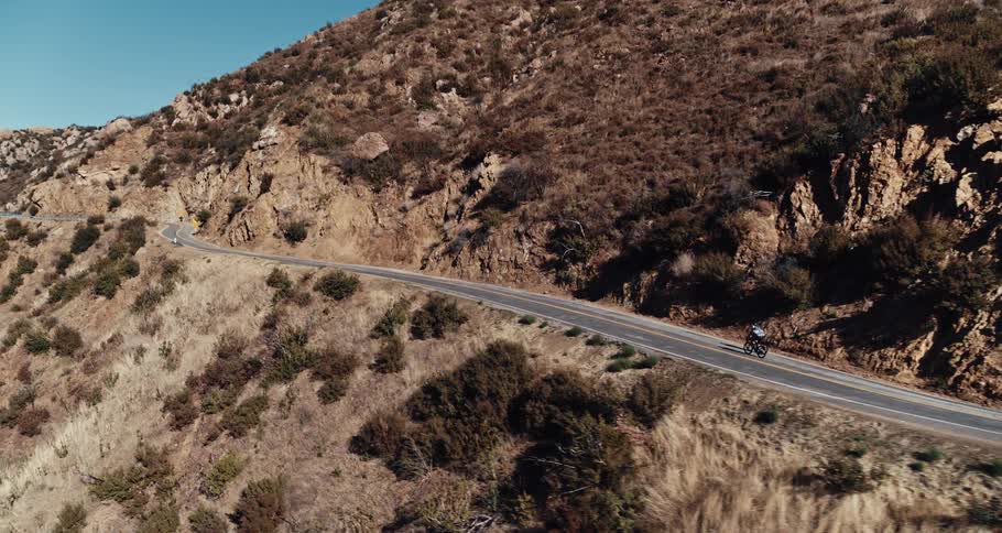 Two people cycle up a mountain road