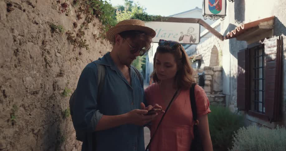 A thief steals a womans camera as she and her boyfriend stop in an alley to look at their phone