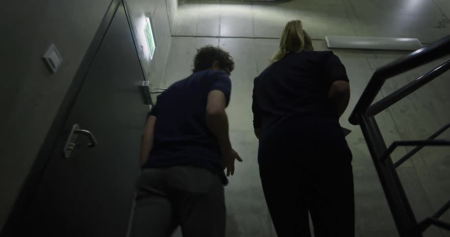 A man and a woman walking up a staircase with a banister