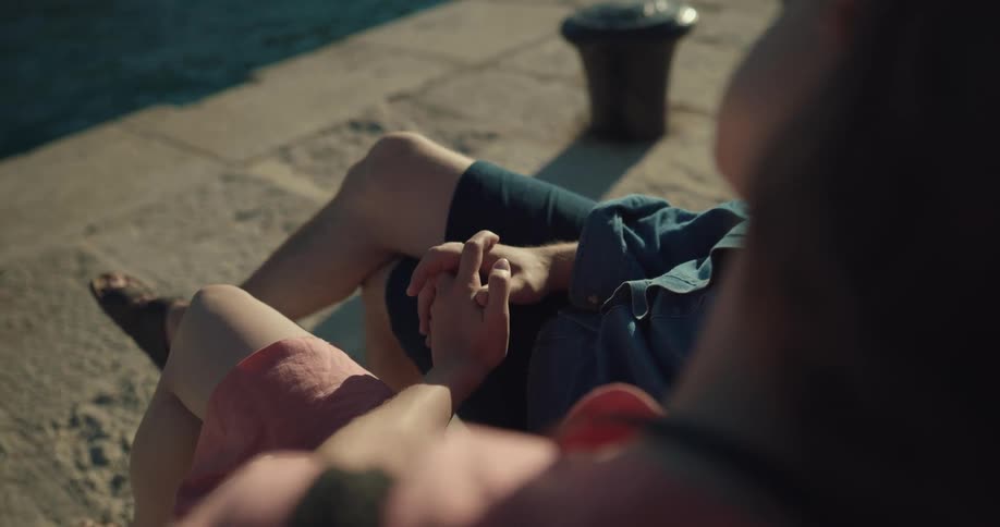 Two people are sitting outdoors and sitting by the lake