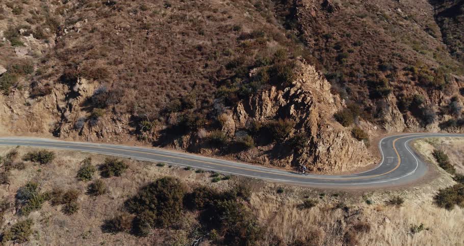 Two people are riding bicycles on a winding mountain road