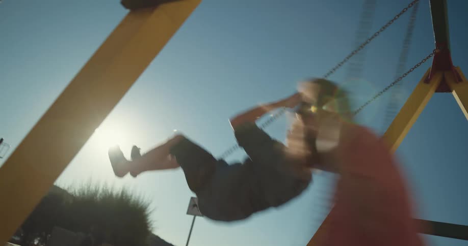 A man and woman swing side by side on a swing set on a sunny day