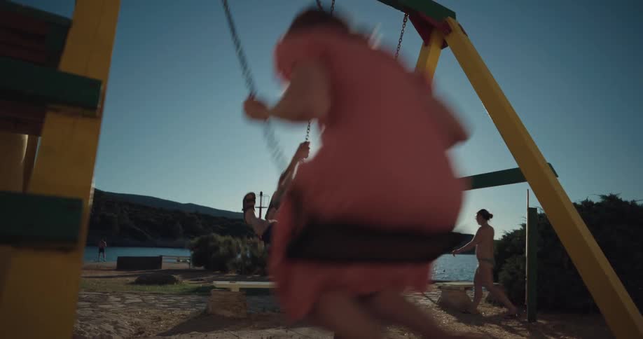 Young happy couple on vacation playing on a swing set in a playground