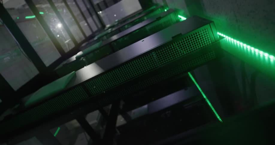 Green neon lights line the sides of elevators in a long hallway