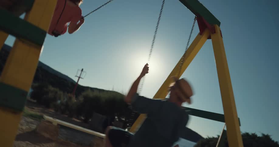 Man and woman swing on a swing set near the lake