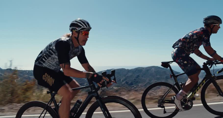 Two bicyclists pedaling up a mountain road on a clear day