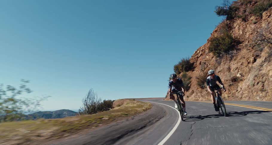 Two bicyclists ride down a curvy mountain road