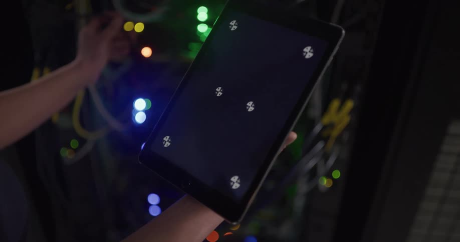 Technician holding a tablet with a replaceable screen inside a server room