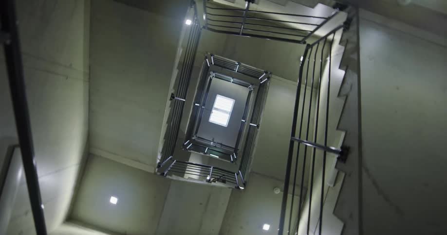 The camera is spiraling around while aimed upwards at a long staircase