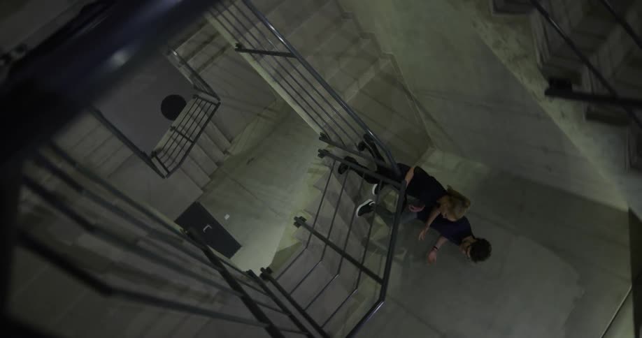 A woman carrying a tablet walks beside a man in a stairwell