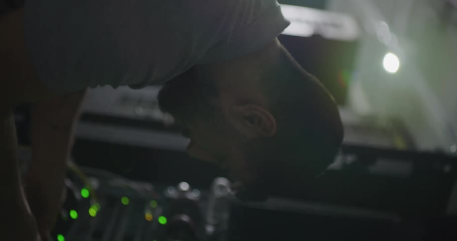 A man in a room working on a server rack with wires and lights