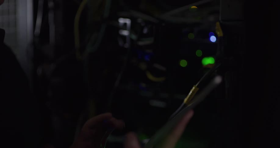 A woman taps on a tablet while standing and working on servers