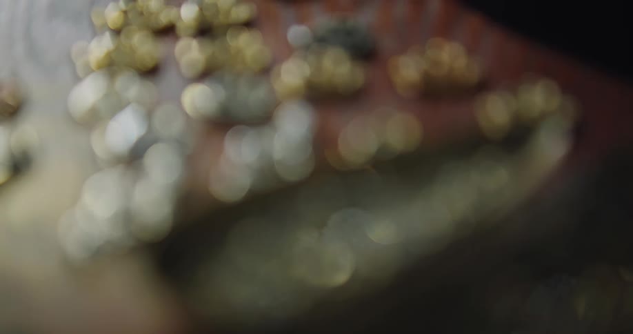 Gold and silver trinkets on a wooden table next to a small bowl full of tiny jewels