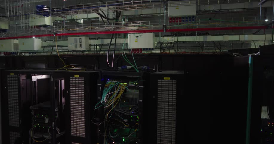 A flare of light comes in over a group of machines in a server room