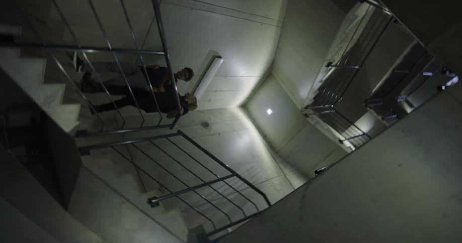 Coworkers talk as they walk down an enclosed concrete staircase