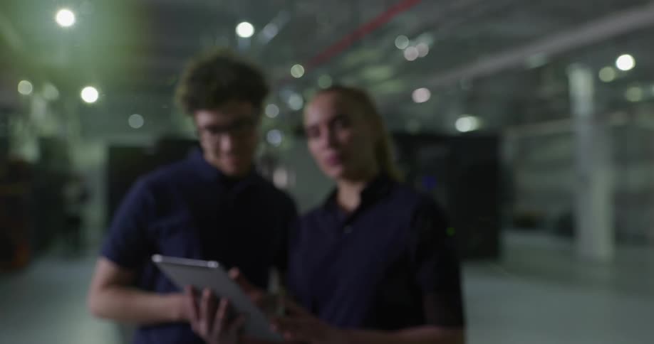 Coworkers hold discussion in data server facility while one holds tablet