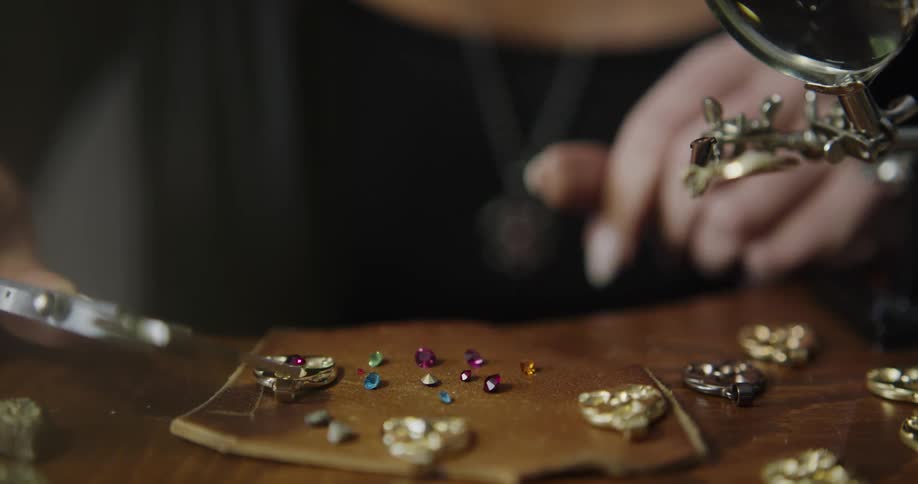 A jeweler picks up a gem to put in a ring setting