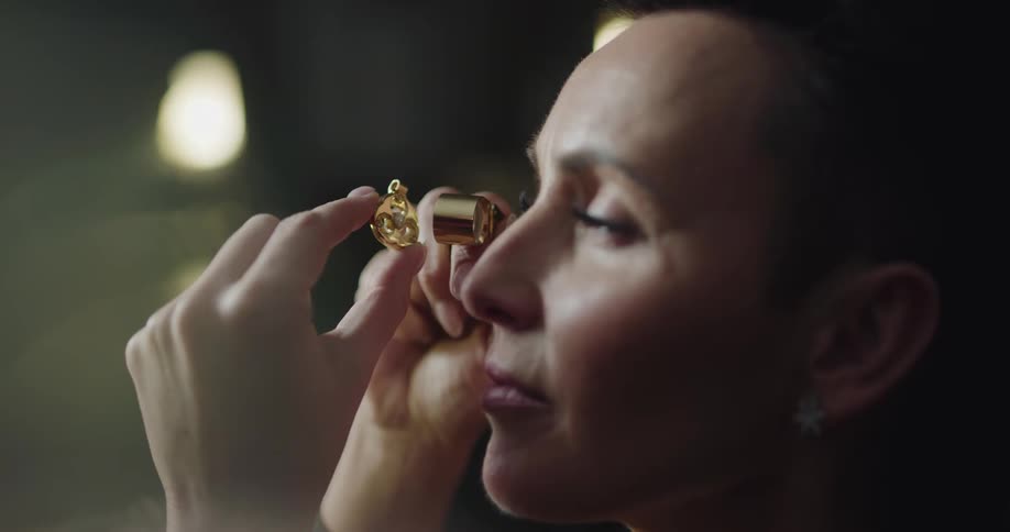 A female jewelry maker carefully inspects a large gemstone using an eyepiece