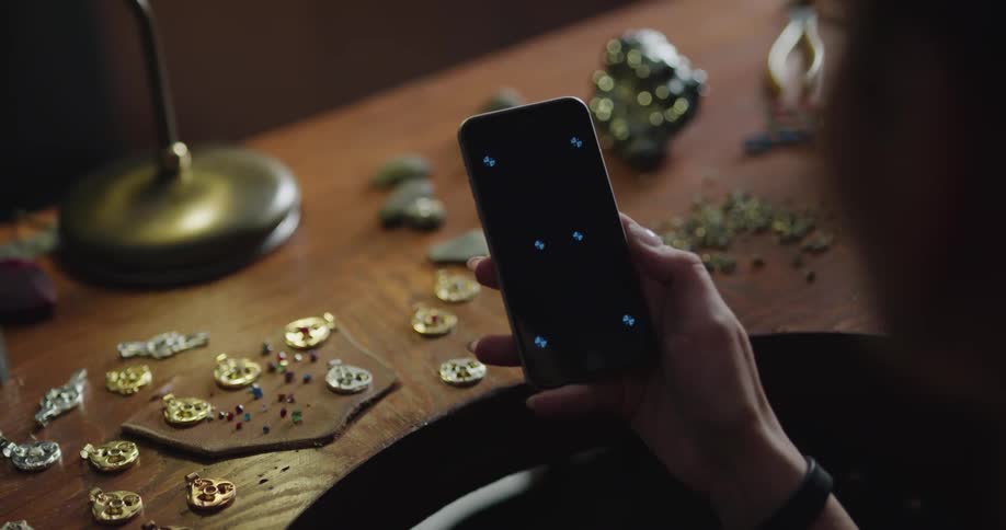 Woman taps the screen of her cellphone with her thumb while she is next to a table