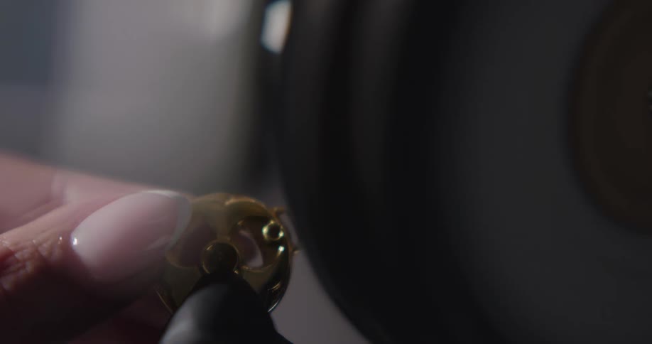 A woman in a room polishing a piece of jewelry with a tool