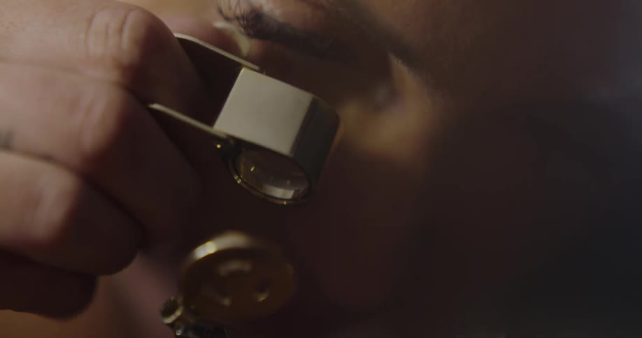 A woman examining a metal key with a magnifier