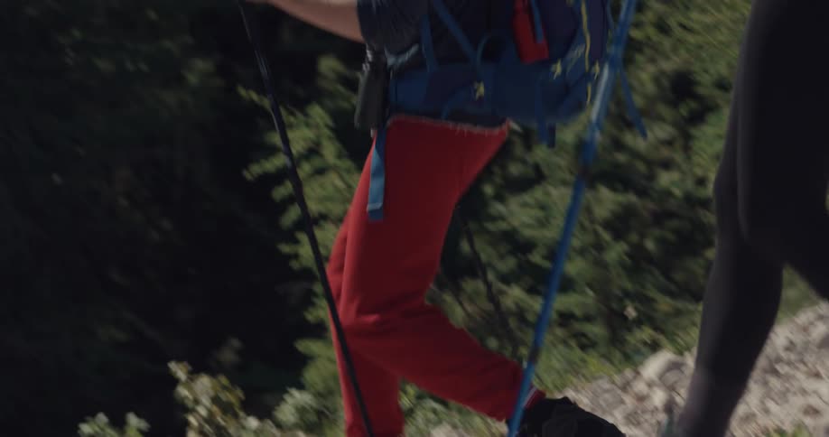 A man slips on a rocky slope as he and a woman hike using poles