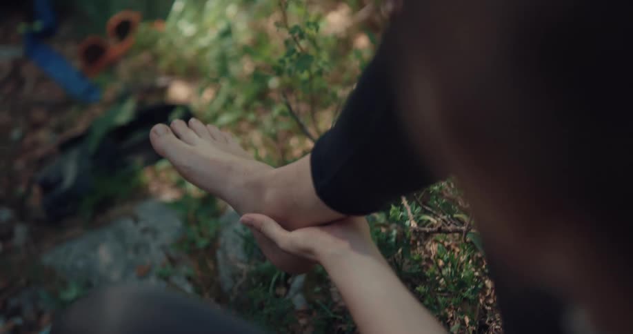 Woman hiking on the forest sitting on the floor resting her hurt ankle