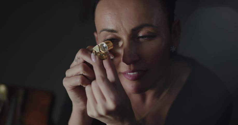 A jewelry is looking at a stone with a magnifying glass