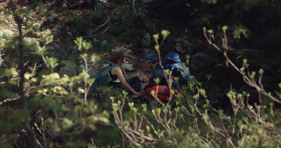 Injured woman sitting on the forest floor after a hiking accident