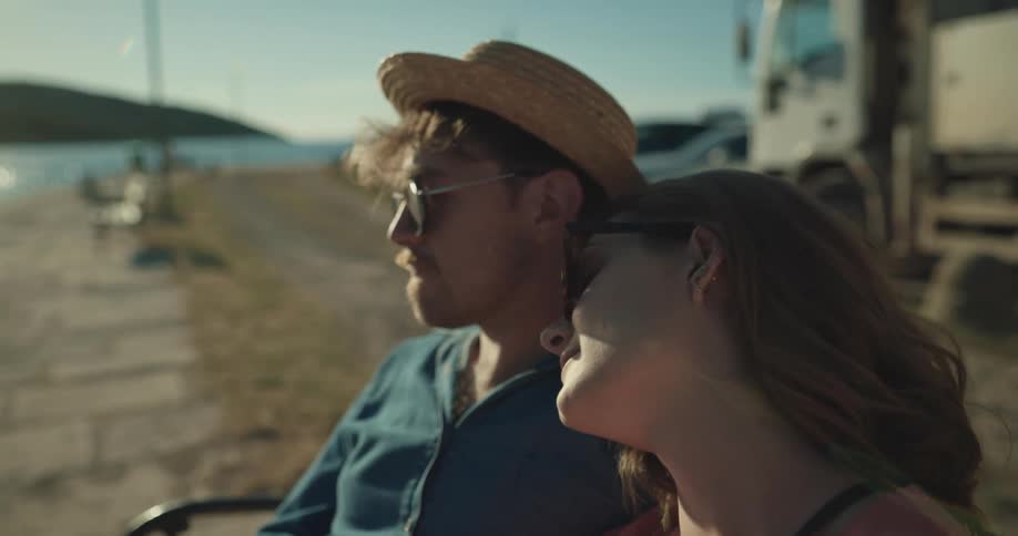 Young couple on vacation sitting on a bench in a pier at morning