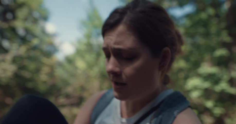 Woman hiking in the woods sits on the floor holding her knee in pain