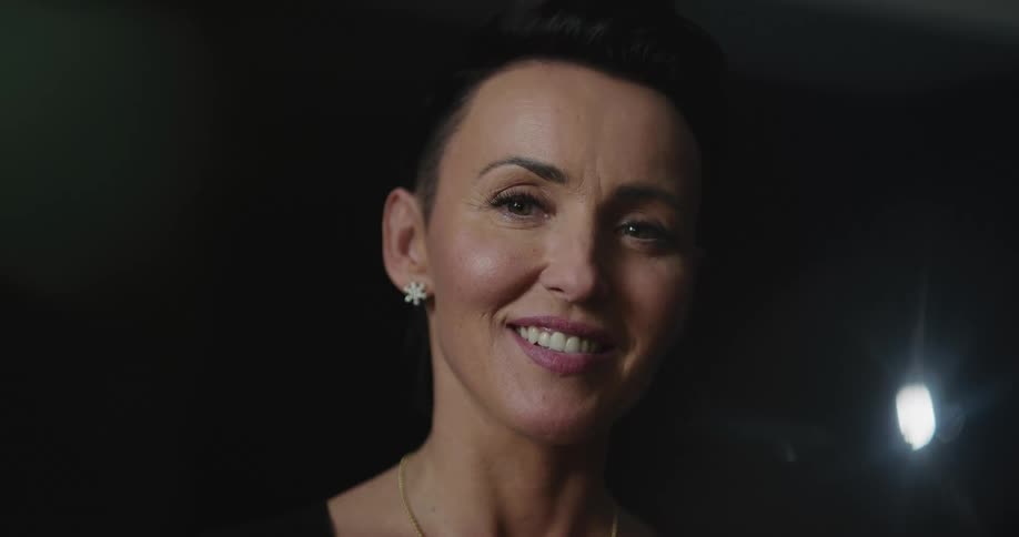 A woman looks up and smiles with a light glowing behind her