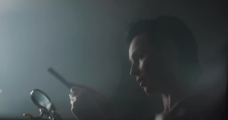 Jeweler manually filing a piece inside a dimly lit workshop