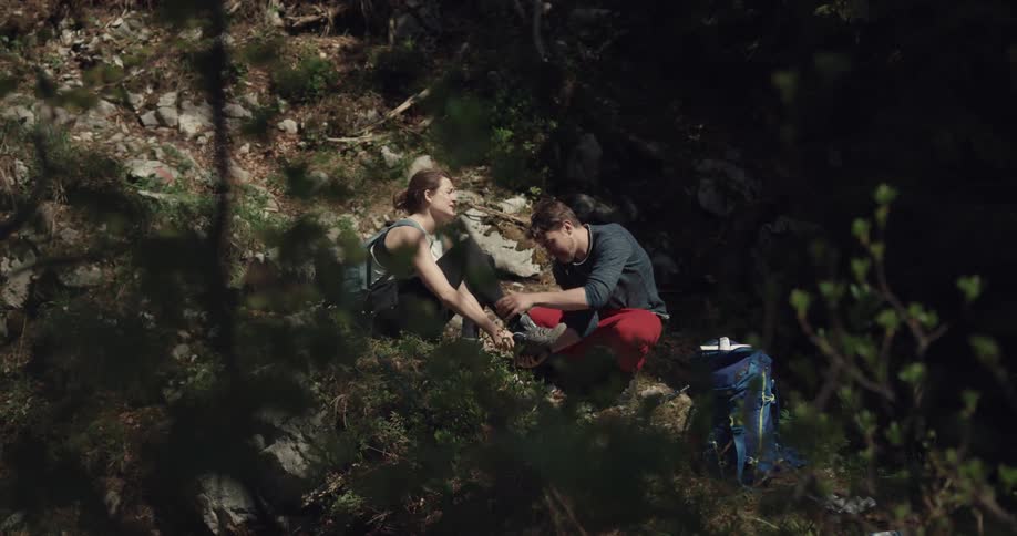 A man helping a woman that got hurt on a hike