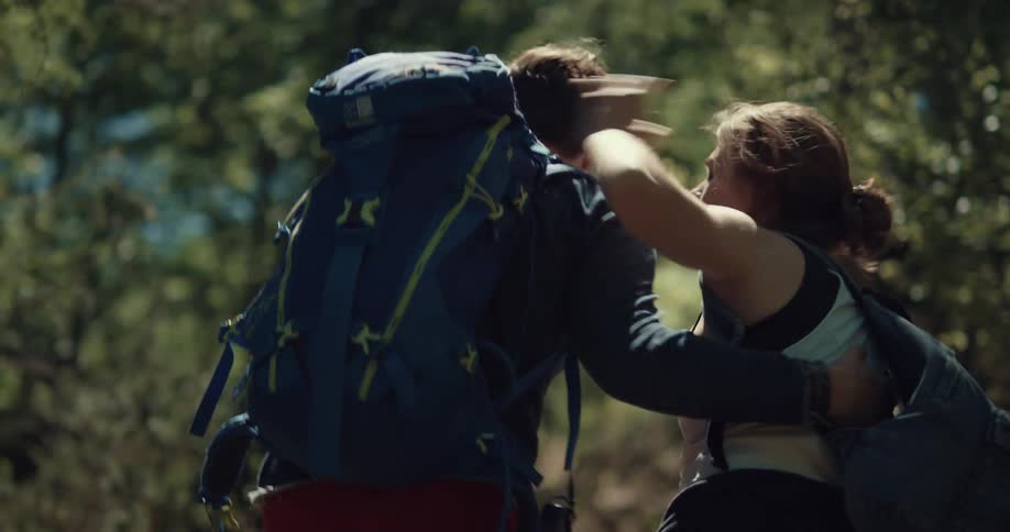 A man assists a woman who trips as they hike